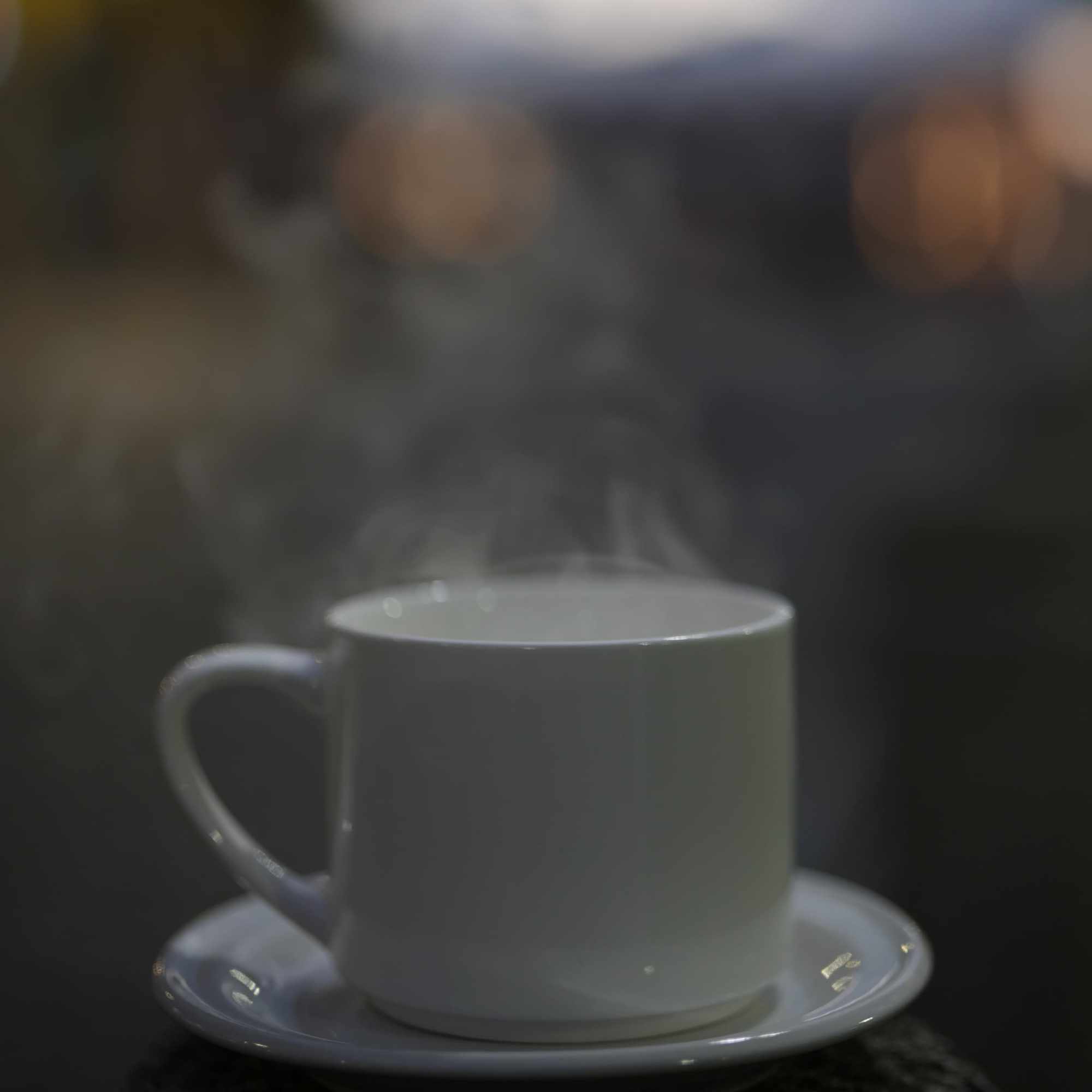 Taza de café AM humeante en penumbra